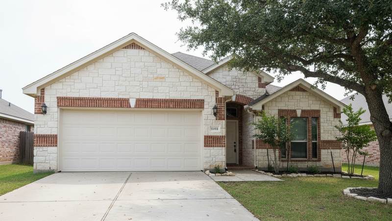 Limestone and brick Central Texas home with a two car garage door facing a concrete driveway